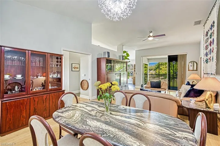 Dining space featuring visible vents, baseboards, light wood-style floors, and ceiling fan with notable chandelier