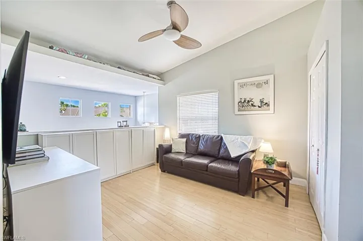 Living area with baseboards, light wood-style floors, ceiling fan, and vaulted ceiling