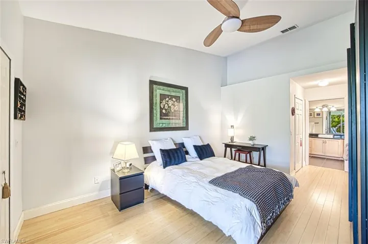 Bedroom featuring baseboards, visible vents, ensuite bath, ceiling fan, and light wood-type flooring