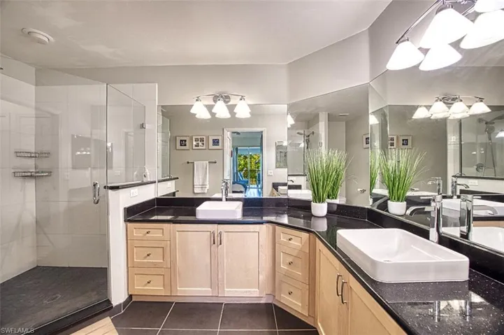 Bathroom featuring tile patterned floors, a shower stall, and a sink