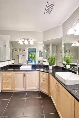 Bathroom featuring a shower with shower door, visible vents, vanity, and tile patterned flooring