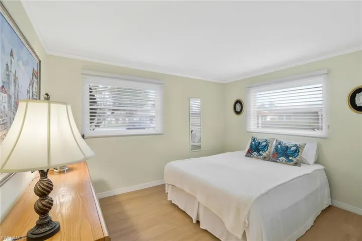 Bedroom with crown molding, light hardwood / wood-style floors and large closet
