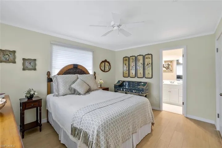 Bedroom featuring multiple windows, light hardwood / wood-style flooring, ceiling fan, large closet and ensuite bathroom