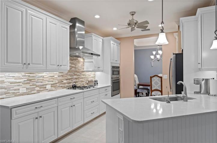 Gourmet kitchen with under counter lighting, wall oven and microwave, and overhead hood