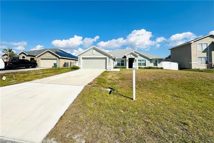 Ranch-style house featuring a front lawn, concrete driveway, an attached garage, and a long driveway