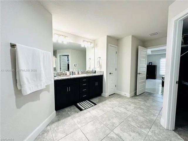 Full bathroom featuring double vanity and baseboards
