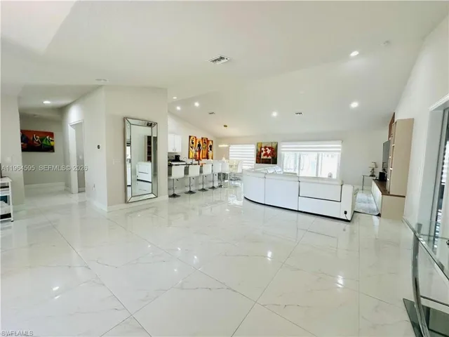 Living room featuring vaulted ceiling, recessed lighting, and light marble finish floors
