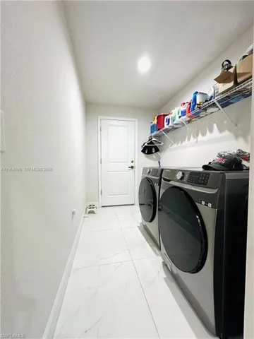 Laundry room featuring light marble finish floors and independent washer and dryer