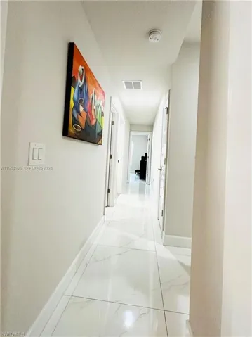 Corridor with baseboards and light marble finish floors