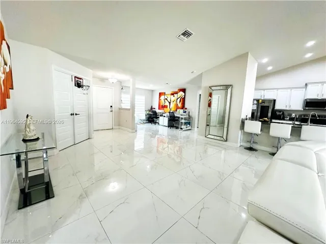 Living area featuring recessed lighting, light marble finish flooring, and vaulted ceiling