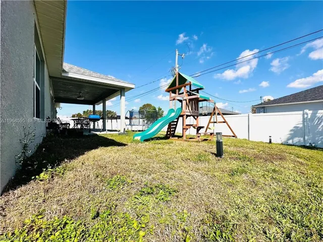 Fenced backyard featuring a playground and a patio area