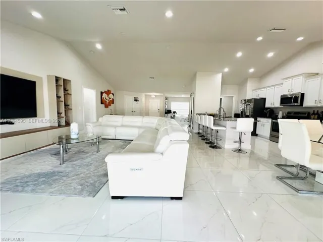 Living room with lofted ceiling, recessed lighting, and light marble finish flooring