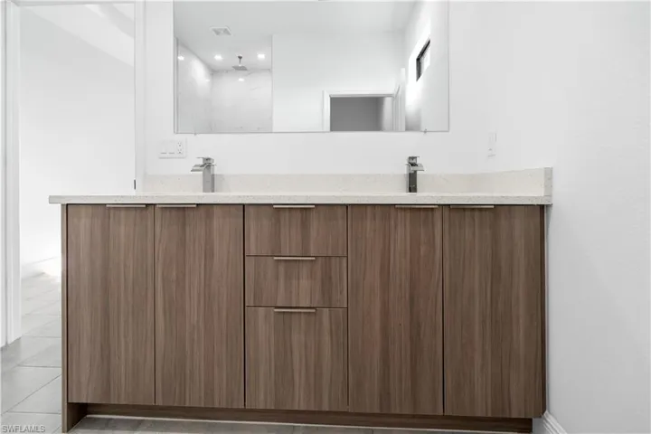 Full bathroom featuring double vanity, a shower, and recessed lighting