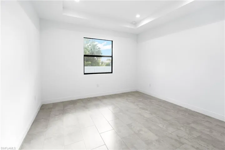 Empty room featuring a tray ceiling and recessed lighting