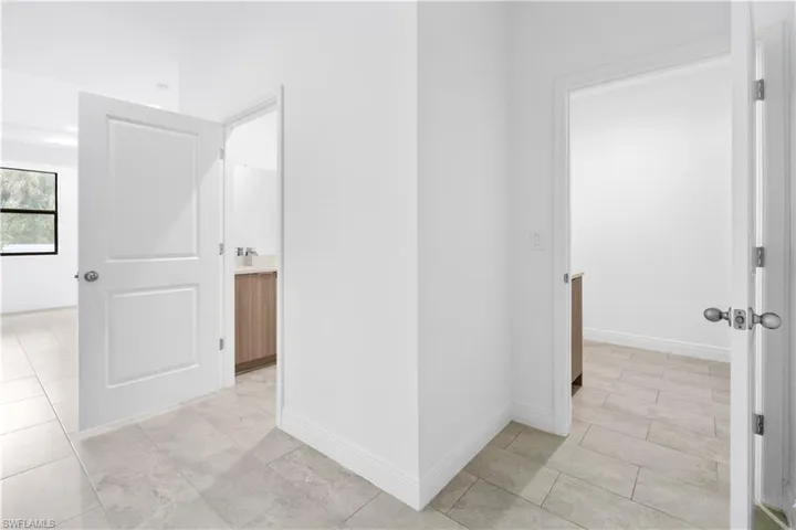 Corridor featuring light tile patterned flooring and baseboards