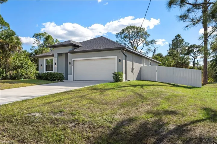 View of front of house featuring stucco siding, a gate, concrete driveway, a garage, and roof with shingles