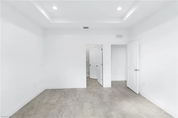 Unfurnished bedroom with recessed lighting, a raised ceiling, and ensuite bathroom