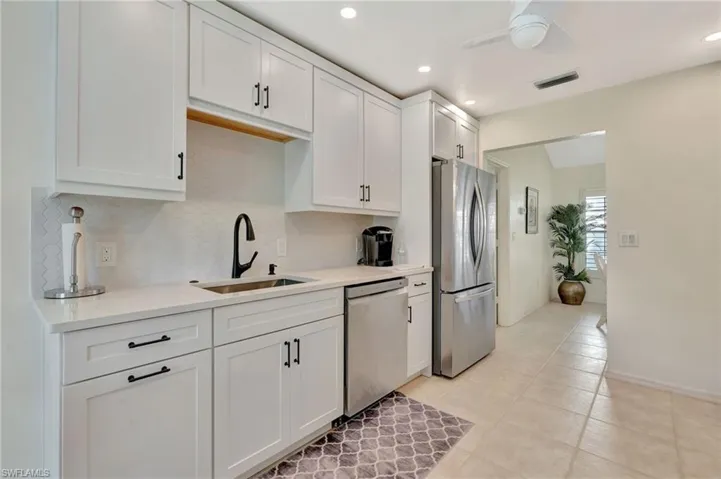 Kitchen featuring stainless steel appliances, decorative backsplash, light countertops, white cabinets, and recessed lighting
