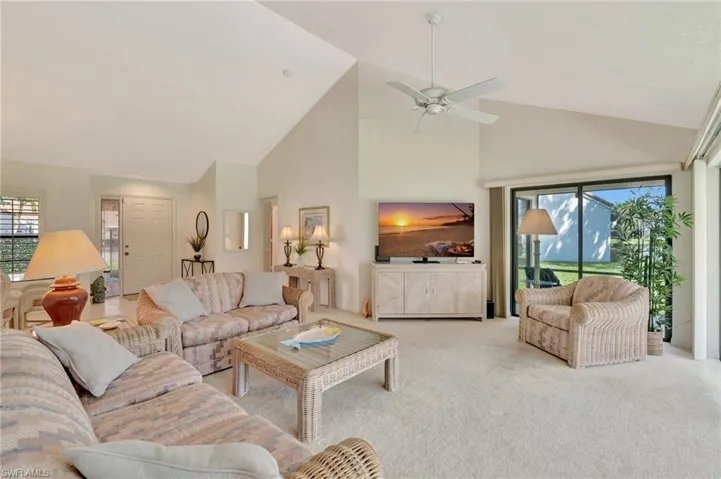 Living room featuring high vaulted ceiling, light carpet, and ceiling fan