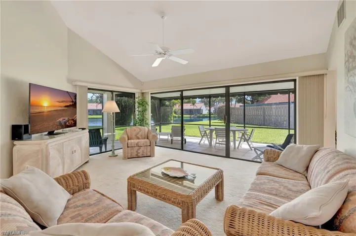 Living room featuring carpet, ceiling fan, high vaulted ceiling, and plenty of natural light