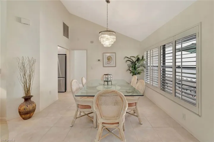 Dining area featuring a chandelier, light tile patterned floors, and high vaulted ceiling