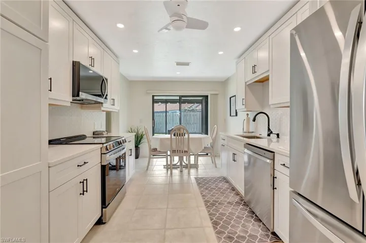 Kitchen featuring appliances with stainless steel finishes, backsplash, light countertops, white cabinetry, and recessed lighting