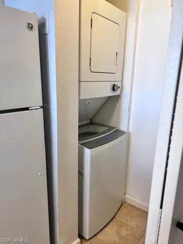 Washroom with estacked washer and dryer and light tile patterned floors