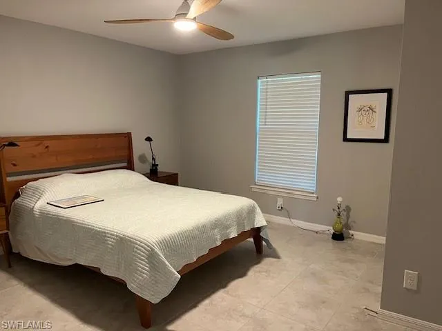 Bedroom featuring ceiling fan, light tile patterned floors, and baseboards