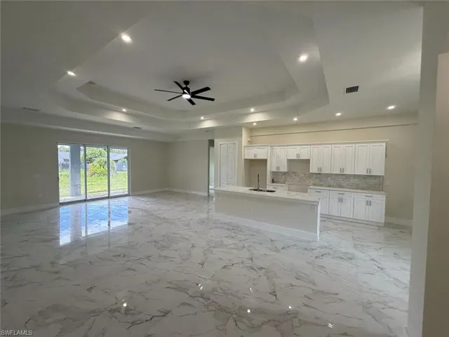 Unfurnished living room with a raised ceiling, recessed lighting, and a ceiling fan