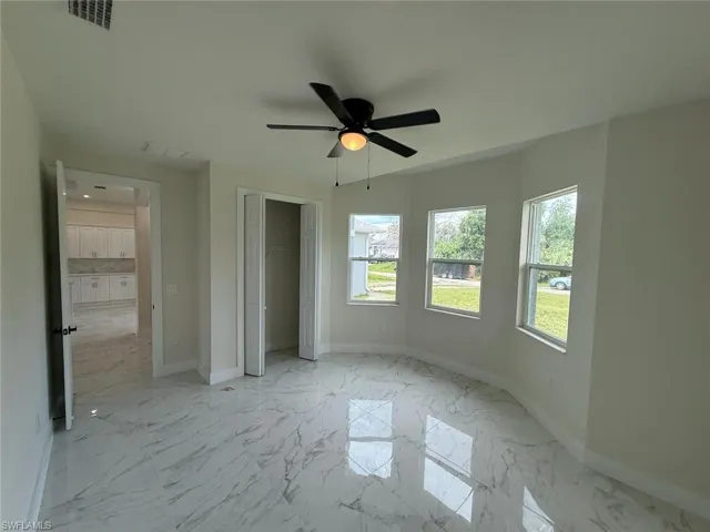 Unfurnished bedroom featuring multiple windows and light marble finish floors
