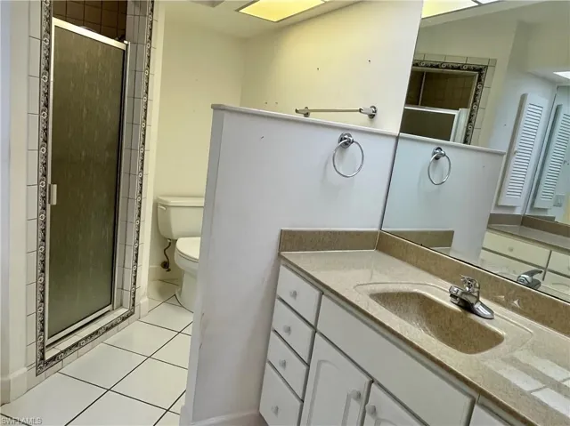 Bathroom with vanity, walk in shower, tile patterned floors, and toilet