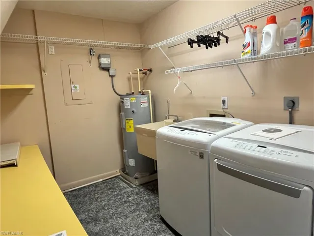 Clothes washing area featuring water heater, sink, and independent washer and dryer