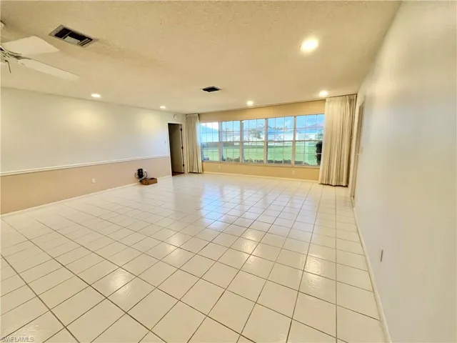 Tiled empty room featuring a textured ceiling and ceiling fan