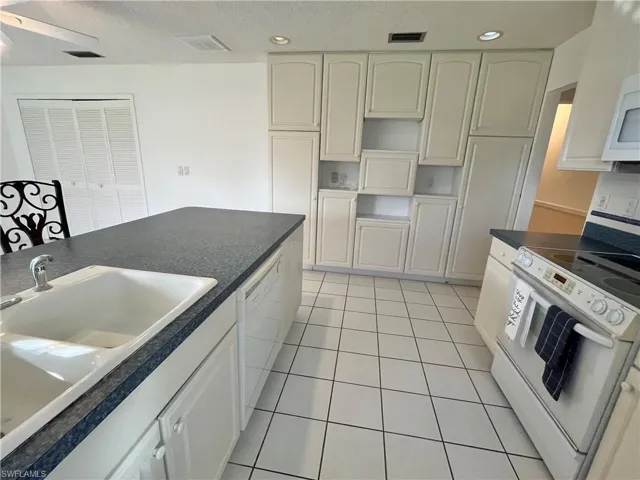 Kitchen featuring sink, ceiling fan, light tile patterned floors, white appliances, and white cabinets