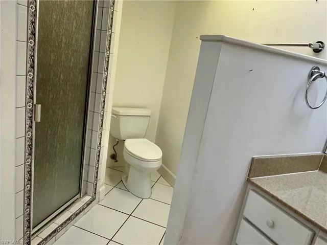 Bathroom featuring vanity, a shower with door, tile patterned flooring, and toilet
