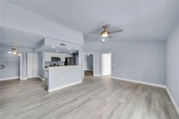 Open-concept living area featuring wood-finish flooring, a contemporary ceiling fan, and a kitchen with stainless steel appliances