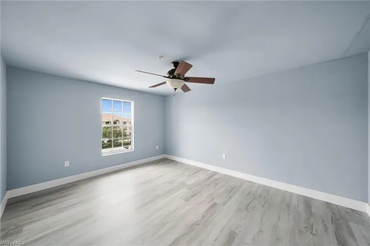 Spacious room featuring wood-finish flooring, light blue walls, and a multi-pane window