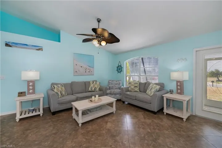 Living area featuring lofted ceiling, a wealth of natural light, with neutral furnishings and coastal decor