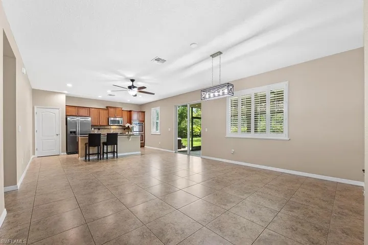 Unfurnished living room featuring ceiling fan with notable chandelier and light tile flooring