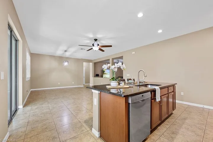Kitchen with dishwasher, a center island with sink, ceiling fan, sink, and light tile floors