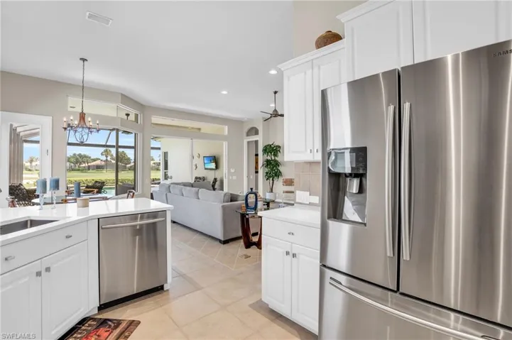 Kitchen featuring appliances with stainless steel finishes, tasteful backsplash, white cabinets, light tile patterned floors, and an inviting chandelier