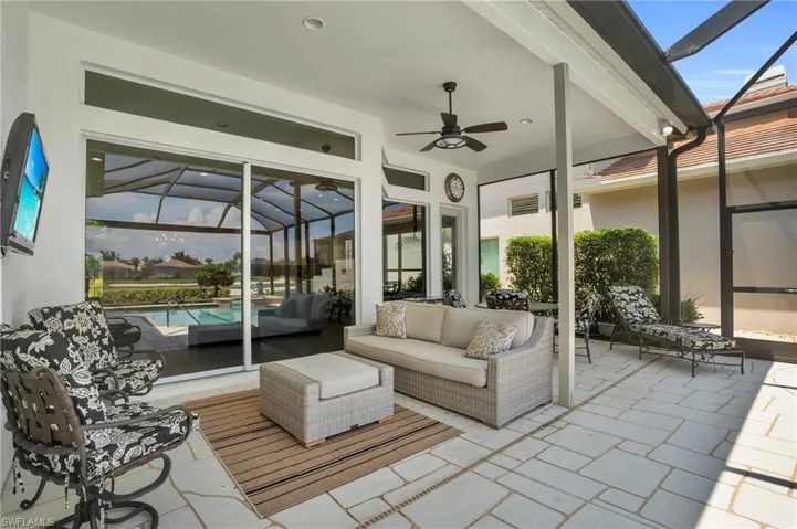 View of patio featuring glass enclosure, ceiling fan, and an outdoor living space