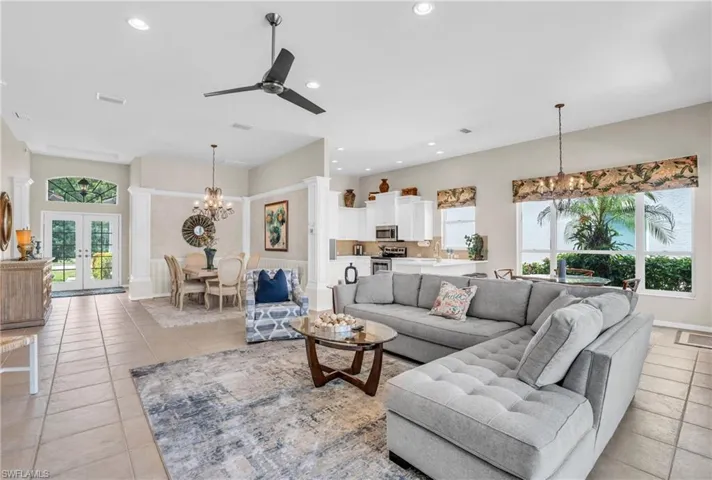 Living room with french doors, ceiling fan with notable chandelier, and light tile patterned floors