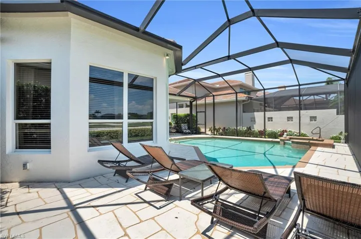 View of pool featuring glass enclosure and a patio