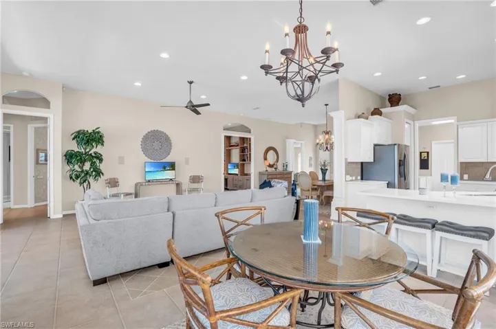 Dining area featuring ceiling fan with notable chandelier, sink, and light tile patterned floors