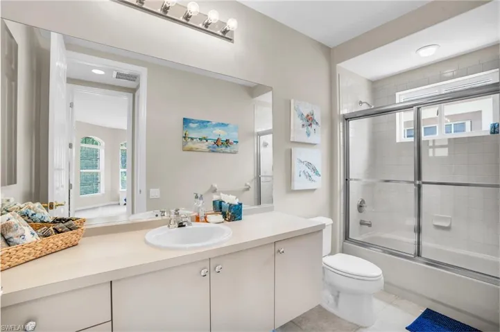Full bathroom featuring enclosed tub / shower combo, tile patterned flooring, vanity, and toilet
