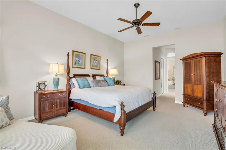 Bedroom featuring ceiling fan, light colored carpet, and ensuite bath