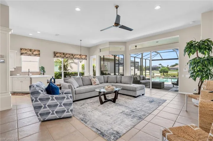 Tiled living room featuring ceiling fan with notable chandelier and sink
