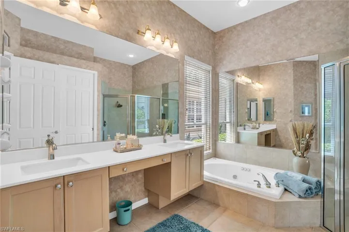 Bathroom featuring vanity, plus walk in shower, plenty of natural light, and tile patterned flooring
