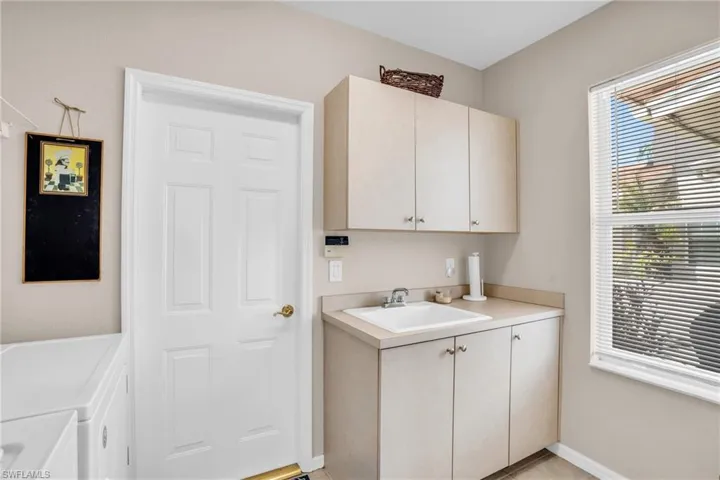 Washroom featuring washer and clothes dryer, sink, and cabinets